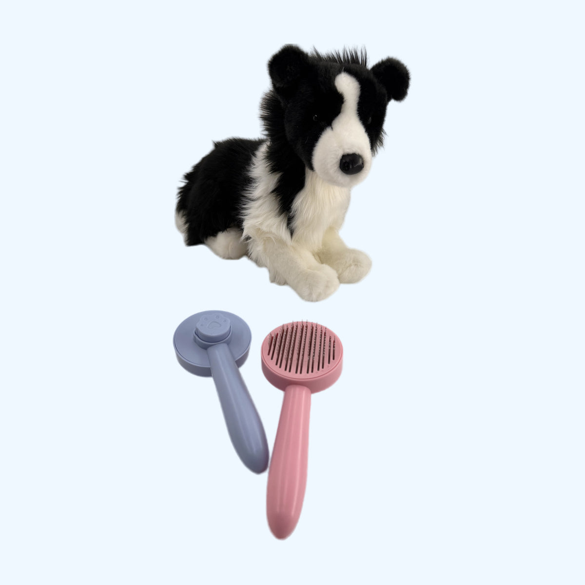 ESSA Self-Cleaning Grooming Brush in Blue and Pink in front of a border collie plush